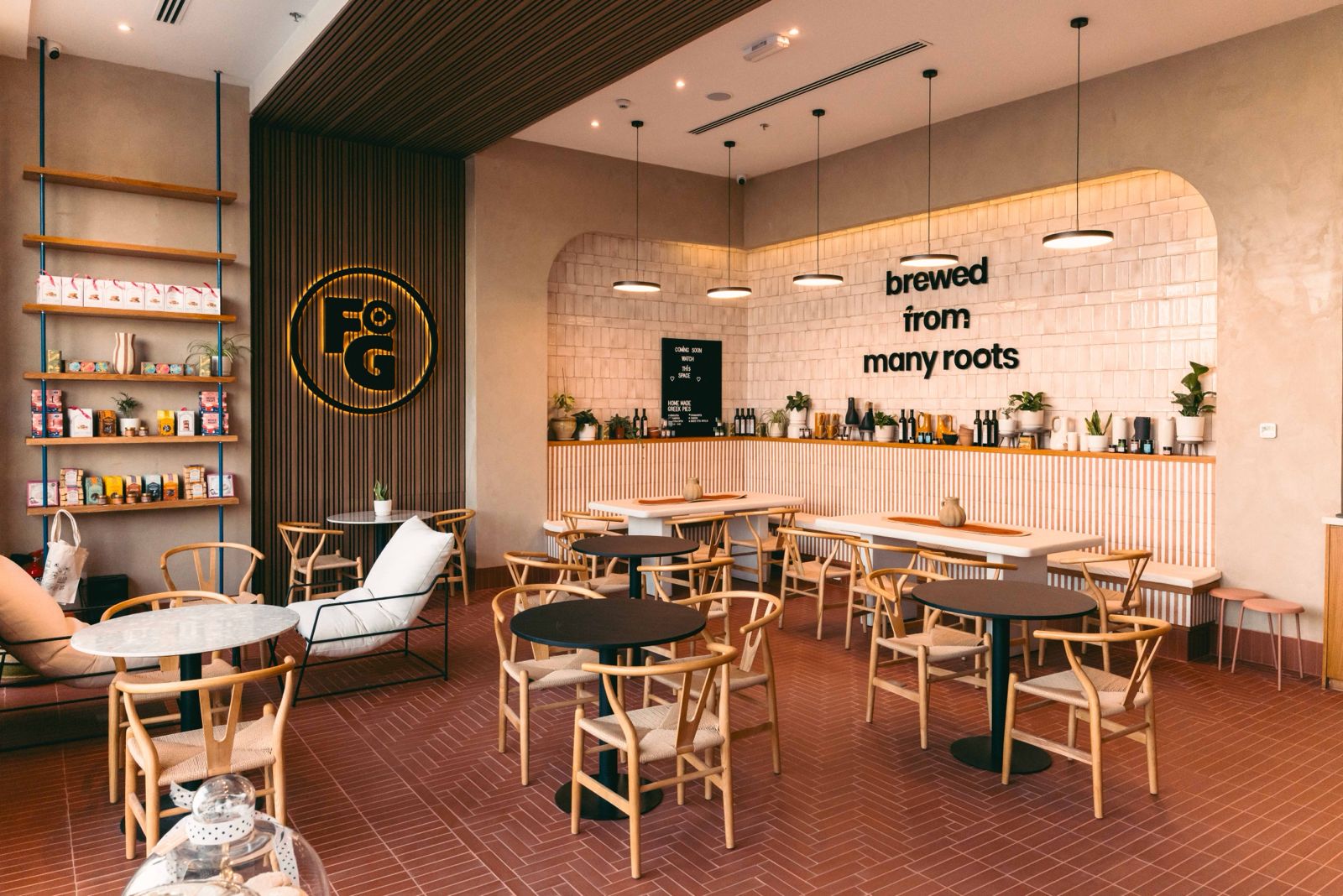 Interior of Freshly Ground coffee shop in Dubai Science Park, with wishbone chairs, terracotta herringbone floors and the tiled 'brewed from many roots' feature wall behind the counter