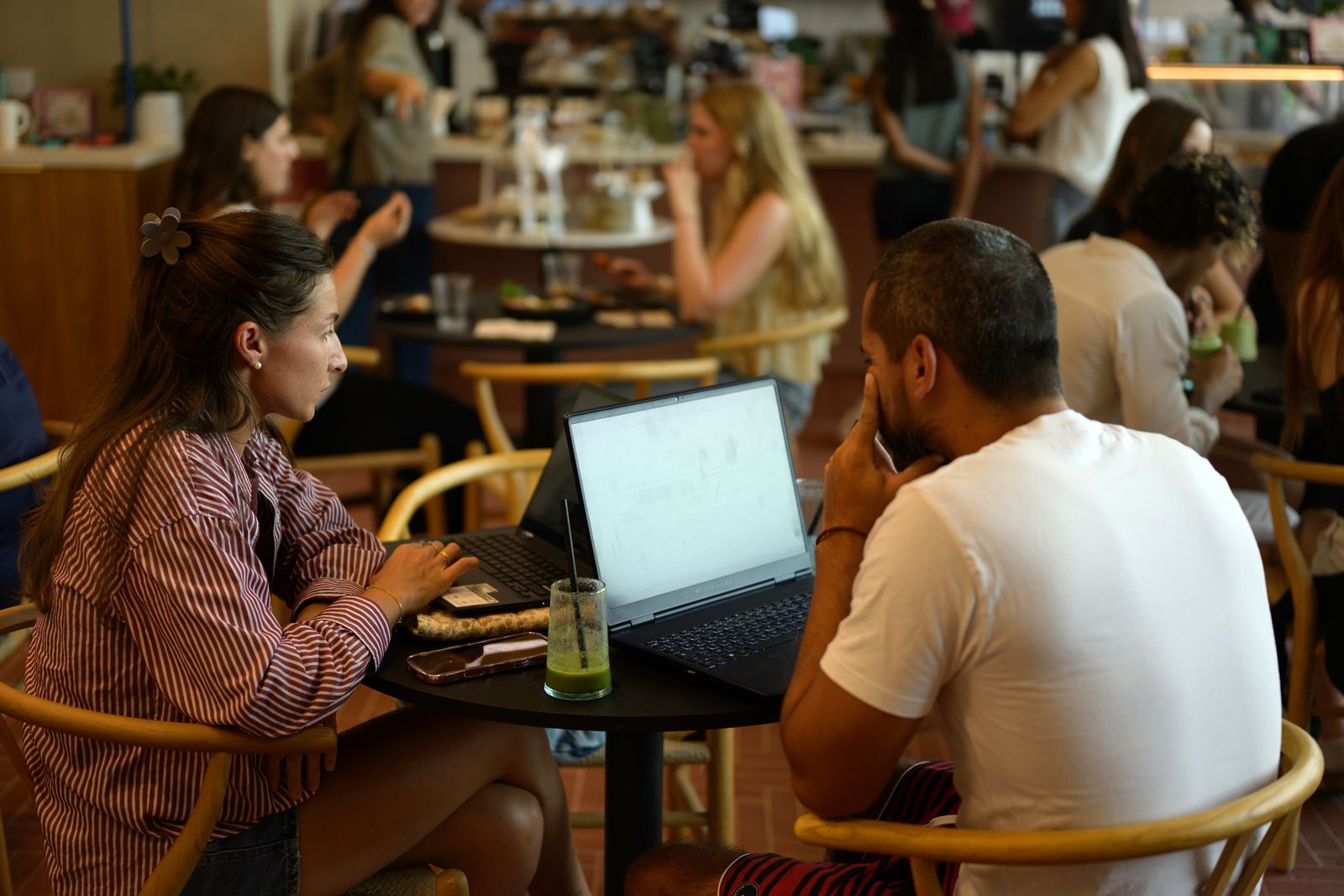 Guests working on laptops over coffee at a table inside Freshly Ground